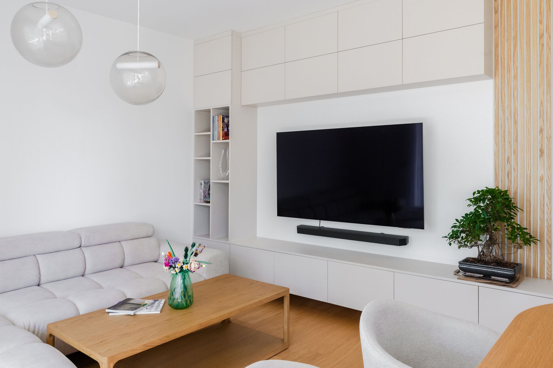 Living room with a light sofa, oak coffee table and a TV wall with a niche