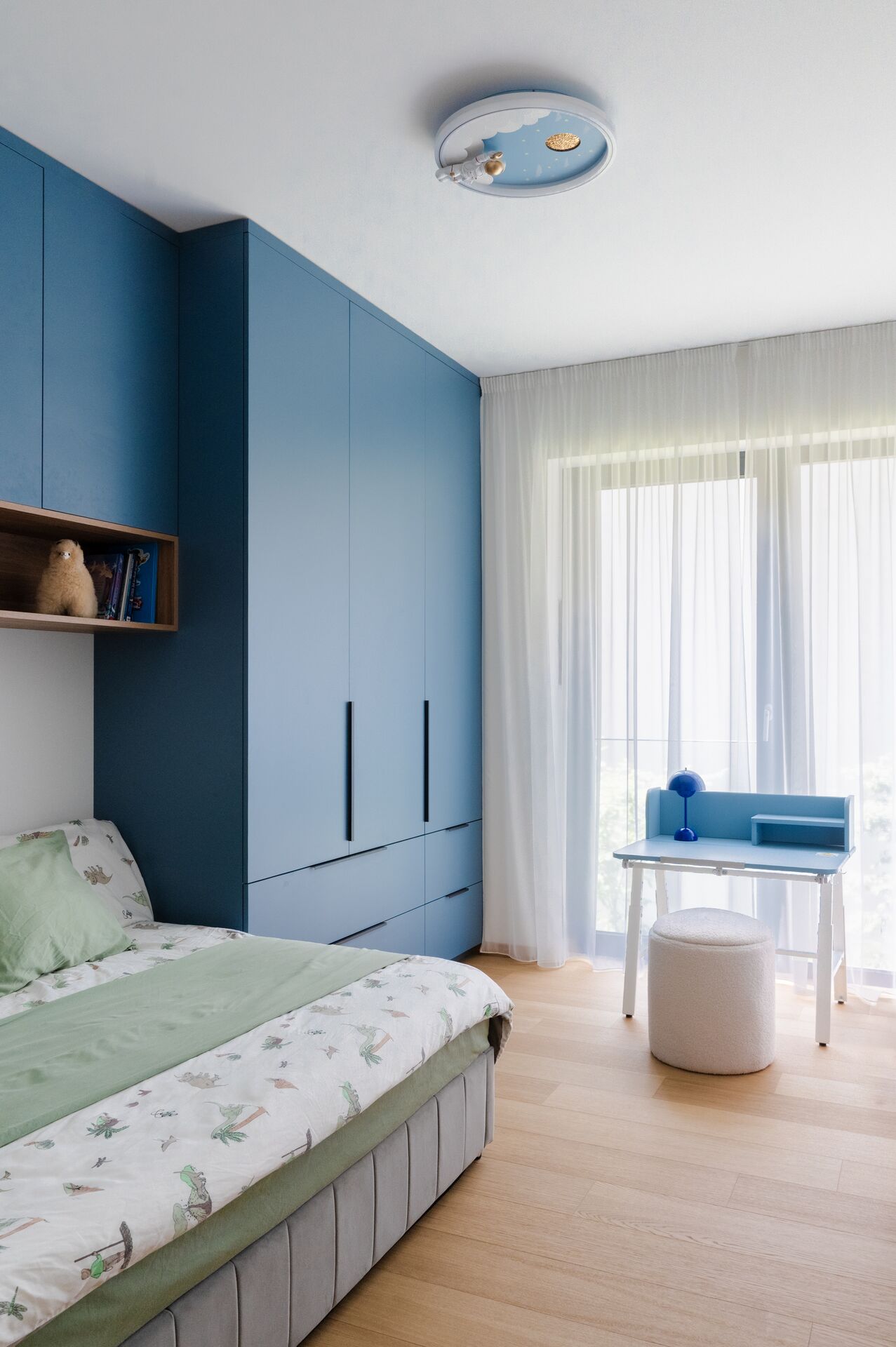 Children's room with a blue built-in wardrobe and a desk by the window